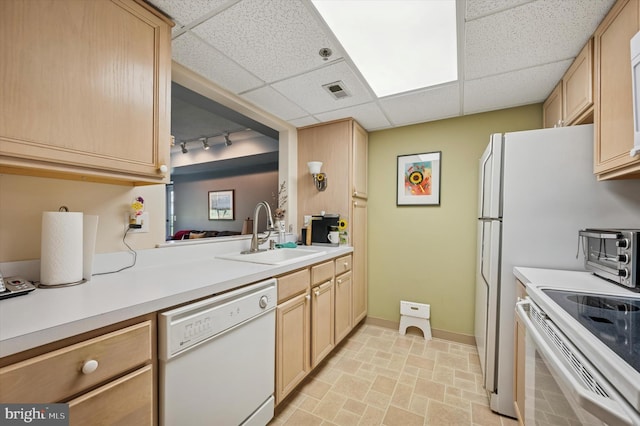 kitchen with light brown cabinets, a drop ceiling, white appliances, and a sink