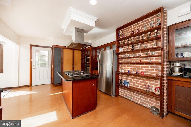 kitchen with island range hood, appliances with stainless steel finishes, dark countertops, and light wood finished floors