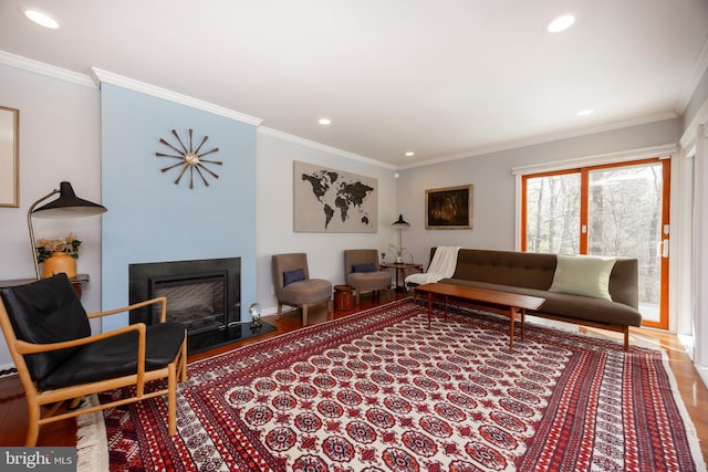 living area featuring ornamental molding, recessed lighting, wood finished floors, and a fireplace
