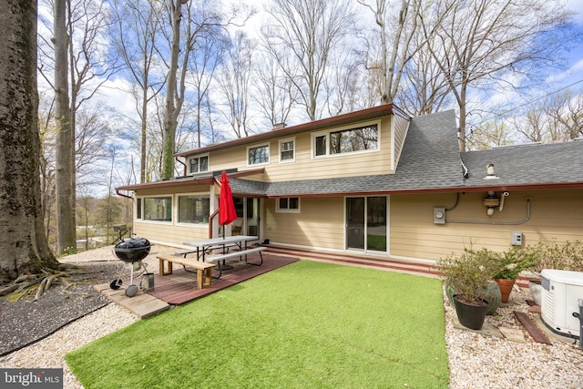 rear view of property with a yard, a shingled roof, and a deck