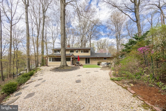 prairie-style home featuring gravel driveway, a patio, and a shingled roof