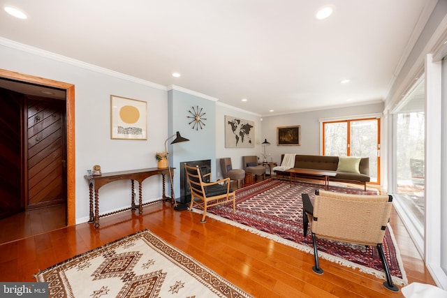 living area with wood finished floors, baseboards, ornamental molding, and recessed lighting