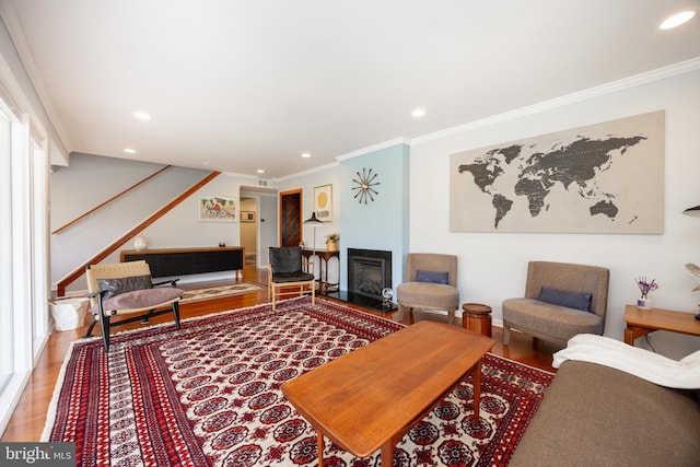 living room featuring crown molding, wood finished floors, recessed lighting, and stairs