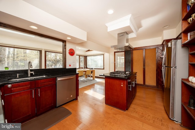 kitchen with dark brown cabinets, appliances with stainless steel finishes, a sink, dark countertops, and island range hood