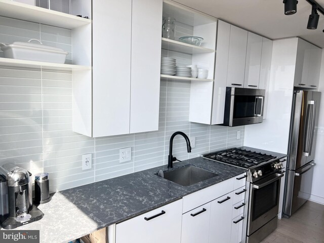 kitchen with open shelves, stainless steel appliances, a sink, backsplash, and white cabinetry