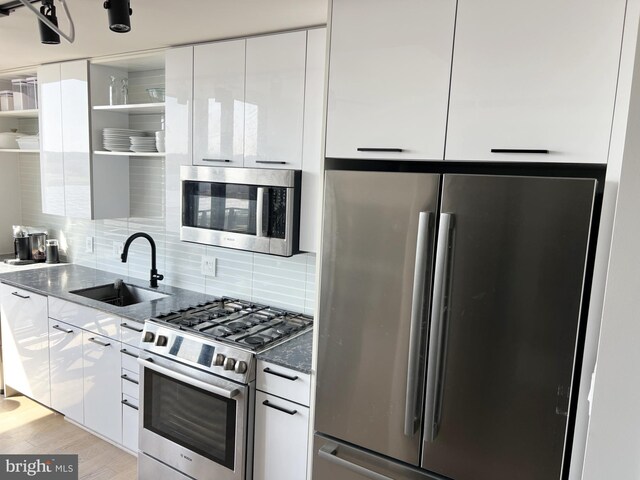 kitchen featuring appliances with stainless steel finishes, a sink, modern cabinets, open shelves, and white cabinets