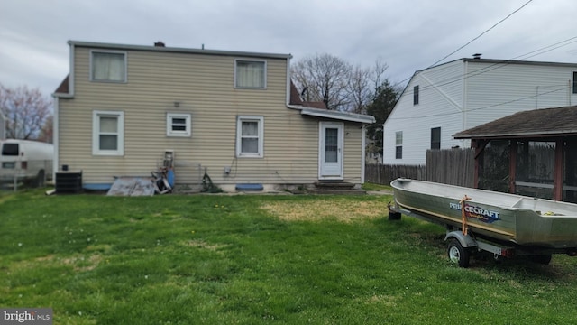 back of property featuring entry steps, fence, a lawn, and central air condition unit