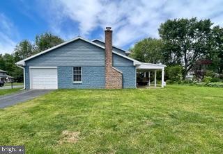 768 Lexington Ave, Hershey, PA 17033 - view of side of property with a chimney, a garage, asphalt driveway, and a yard