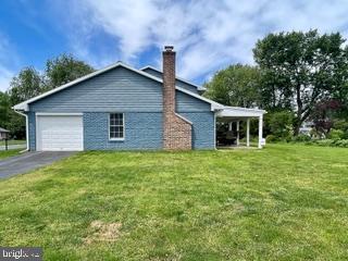 768 Lexington Ave, Hershey, PA 17033 - view of side of property with a chimney, an attached garage, a lawn, and asphalt driveway