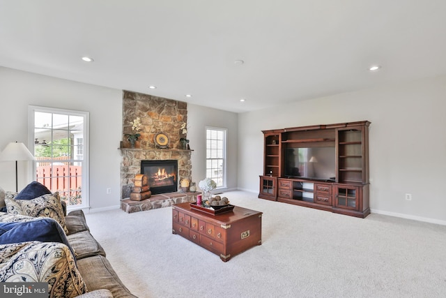 carpeted living area with baseboards, recessed lighting, a stone fireplace, and a wealth of natural light