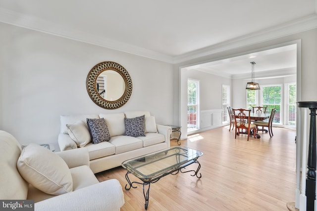 living area featuring light wood-type flooring, wainscoting, and crown molding