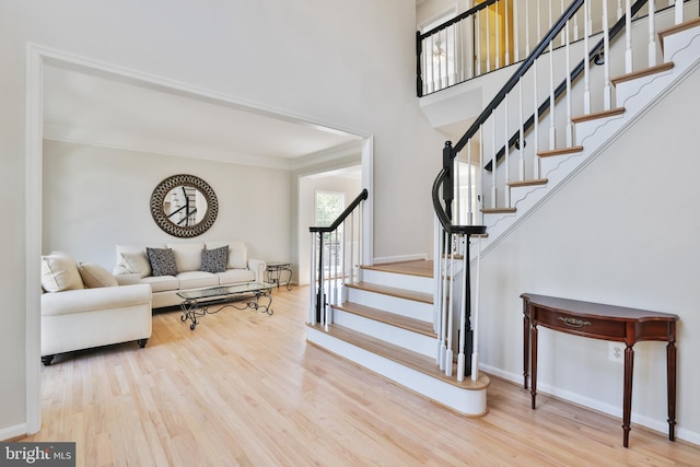 foyer entrance with baseboards, ornamental molding, wood finished floors, and stairway