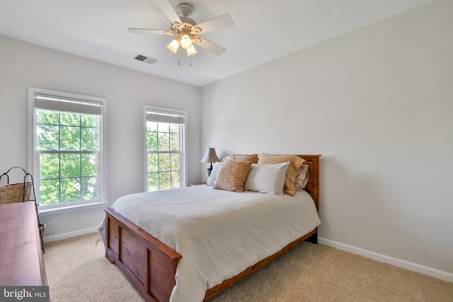 bedroom with baseboards, visible vents, light carpet, and multiple windows
