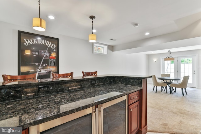 kitchen featuring dark stone counters, recessed lighting, hanging light fixtures, and wine cooler