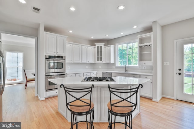 kitchen featuring a kitchen bar, appliances with stainless steel finishes, a sink, recessed lighting, and white cabinetry