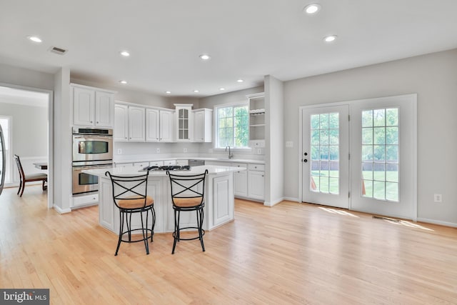 kitchen with a kitchen breakfast bar, a kitchen island, visible vents, white cabinets, and stainless steel appliances