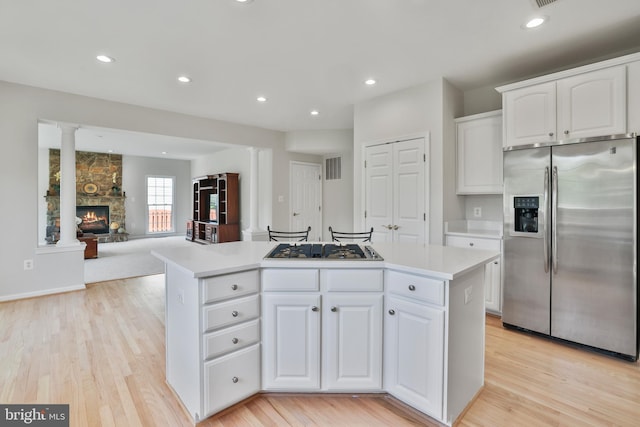 kitchen featuring white cabinets, appliances with stainless steel finishes, light wood-style floors, light countertops, and a center island