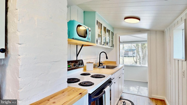 11951 Neale Sound Dr, Cobb Island, MD 20625 - kitchen featuring glass insert cabinets, electric range oven, a sink, light wood finished floors, and white cabinetry
