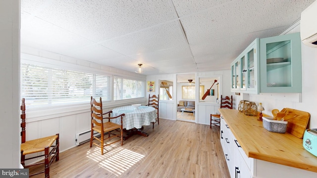 11951 Neale Sound Dr, Cobb Island, MD 20625 - dining area featuring a decorative wall, a baseboard radiator, light wood-type flooring, a wall mounted AC, and a drop ceiling