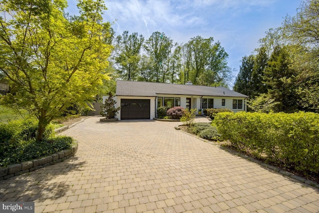 ranch-style house with a garage, decorative driveway, and a chimney