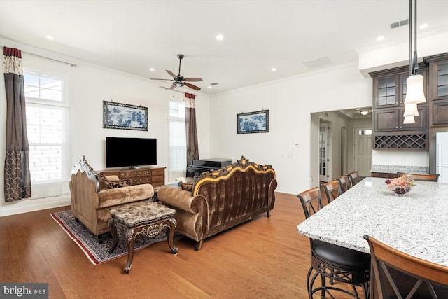 living area with recessed lighting, light wood-type flooring, a ceiling fan, and ornamental molding