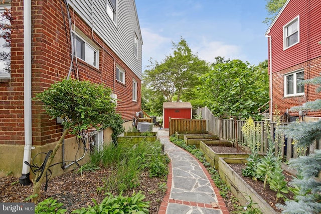 1933 Rollins Dr, Alexandria, VA 22307 - view of yard with a storage unit, a garden, an outdoor structure, central AC, and fence