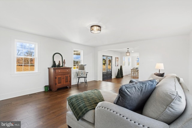 living area featuring dark wood finished floors, baseboards, visible vents, and plenty of natural light