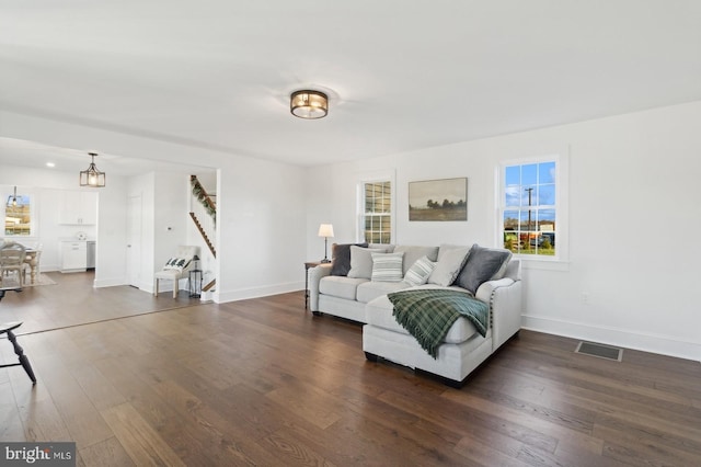 living room with baseboards, visible vents, stairway, and dark wood-type flooring