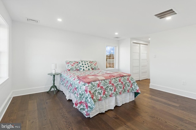bedroom with baseboards, visible vents, and wood finished floors