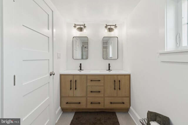bathroom with double vanity, baseboards, and a sink