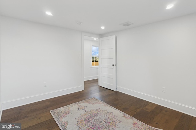 spare room with baseboards, recessed lighting, and dark wood finished floors