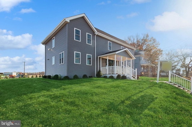 back of property featuring a lawn and a porch