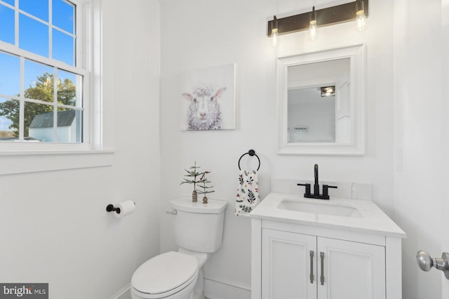 bathroom with toilet, vanity, and baseboards