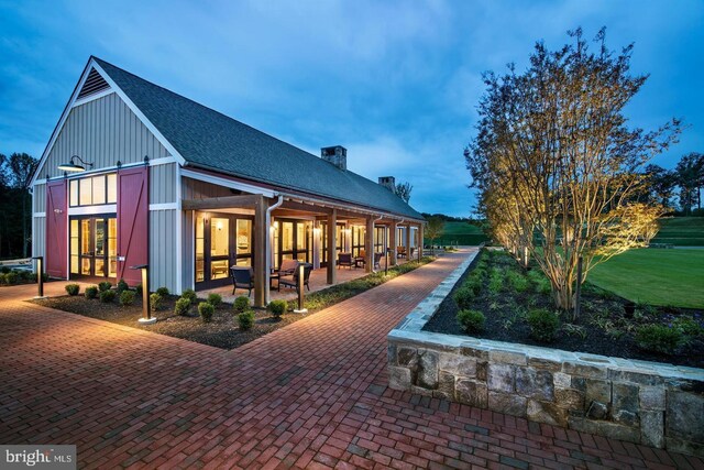 exterior space featuring board and batten siding, a chimney, and a shingled roof