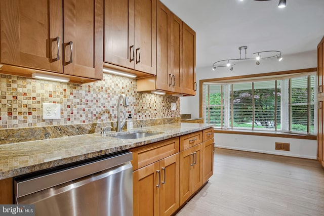 6901 Niles Dr, Laurel, MD 20707 - kitchen with stainless steel dishwasher, a sink, light stone countertops, baseboards, and brown cabinets
