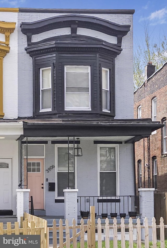 3906 Reisterstown Rd, Baltimore, MD 21215 - view of front of property with covered porch, a fenced front yard, and brick siding