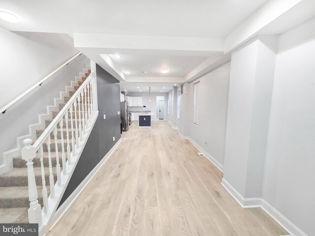3906 Reisterstown Rd, Baltimore, MD 21215 - corridor with light wood finished floors, stairway, a tray ceiling, and baseboards