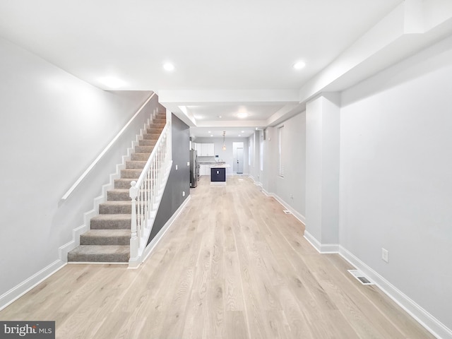 3906 Reisterstown Rd, Baltimore, MD 21215 - hallway featuring stairs, light wood-style flooring, baseboards, recessed lighting, and a tray ceiling