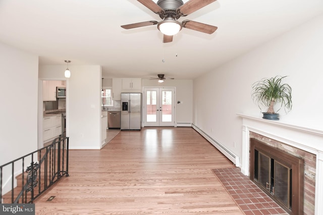 19468 Youngs Cliff Rd, Sterling, VA 20165 - unfurnished living room featuring baseboard heating, a premium fireplace, ceiling fan, light wood-type flooring, and french doors