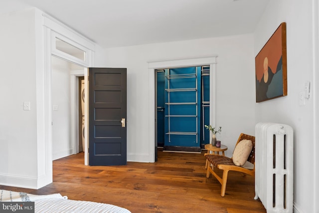 living area featuring radiator, wood-type flooring, and baseboards