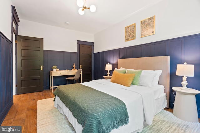 bedroom featuring a wainscoted wall and wood finished floors