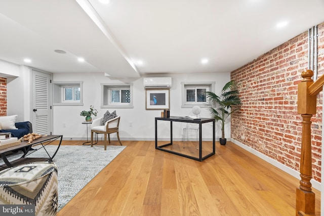 home office featuring an AC wall unit, brick wall, light wood-style floors, baseboards, and recessed lighting