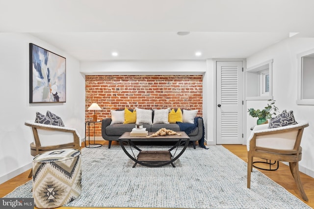 living room with brick wall, baseboards, recessed lighting, and light wood-style flooring