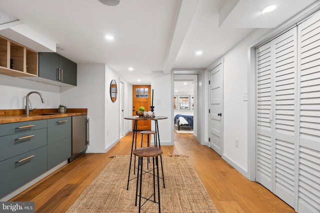 kitchen featuring light wood finished floors, butcher block countertops, a sink, recessed lighting, and open shelves