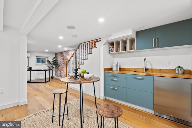 indoor wet bar featuring fridge, stairs, light wood-style floors, baseboards, and a wall unit AC