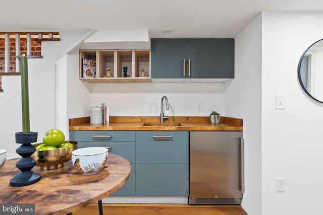 indoor wet bar featuring stainless steel refrigerator, stairs, and wood finished floors
