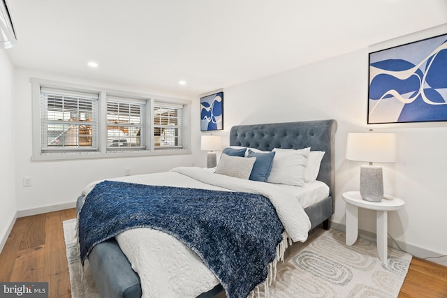 bedroom with baseboards, wood finished floors, and recessed lighting