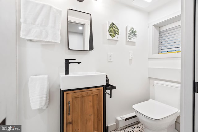 bathroom with a baseboard radiator, toilet, vanity, and baseboards