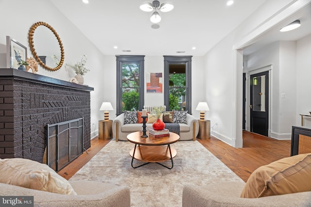 living room featuring wood finished floors, a fireplace, baseboards, and recessed lighting