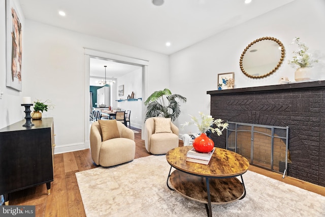 sitting room featuring wood finished floors, a brick fireplace, recessed lighting, and baseboards
